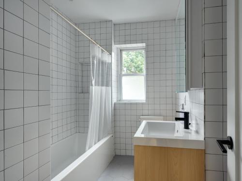 a white tiled bathroom with a sink and a shower at Three Bedroom Brooklynite Suite! in Brooklyn