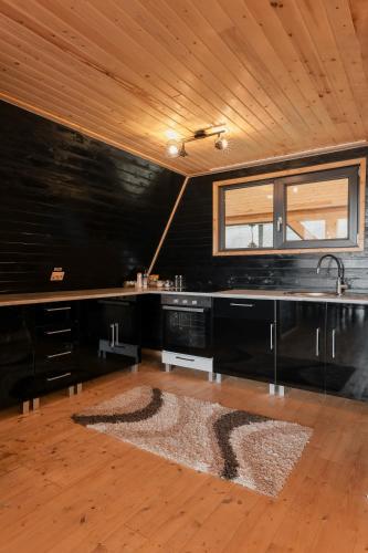 a kitchen with black walls and a sink and a rug at Cabana Vlad Maramureș in Deseşti