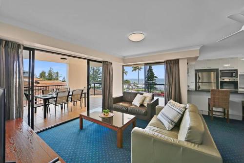 a living room with a couch and a table and a kitchen at Ocean Breeze 3BR Apartment in Bargara
