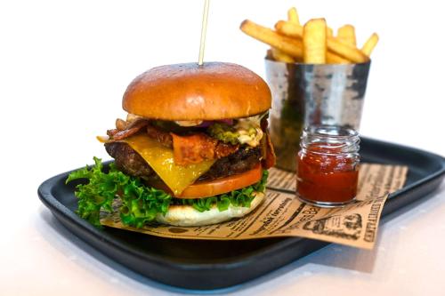 a hamburger on a black plate with french fries at Park Inn by Radisson Oslo Airport Hotel West in Gardermoen