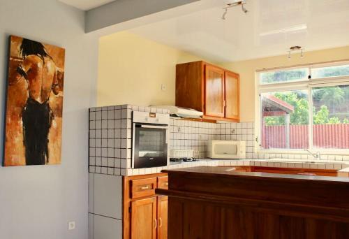 a kitchen with wooden cabinets and a painting on the wall at Tekauhivai Lodge in Uturoa