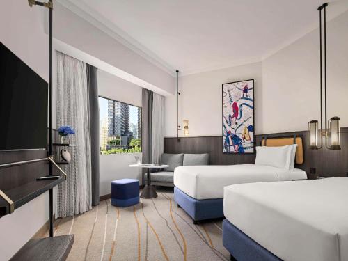 Habitación de hotel con 2 camas y sofá en Pullman Singapore Orchard en Singapur