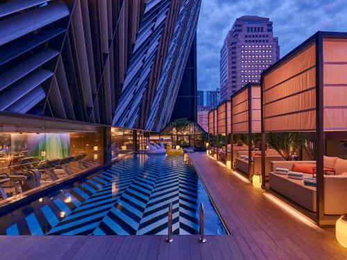 a building with a pool in the middle of a city at Pullman Singapore Orchard in Singapore