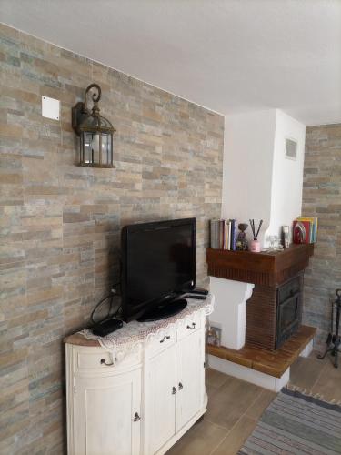 a living room with a television on a brick wall at O Mundo da Lua in Azeitao
