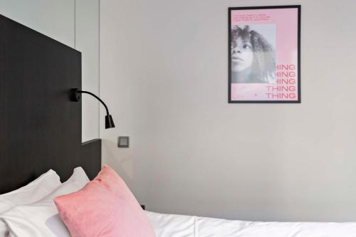 a bed with a pink pillow and a picture on the wall at Aiden by Best Western Stockholm Solna in Solna