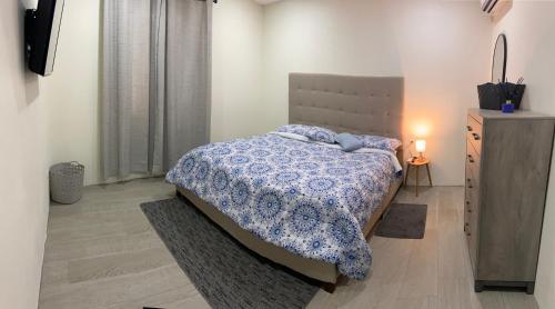 ein Schlafzimmer mit einem Bett und eine Kommode mit einer Lampe in der Unterkunft Paraguana Inn in Noord