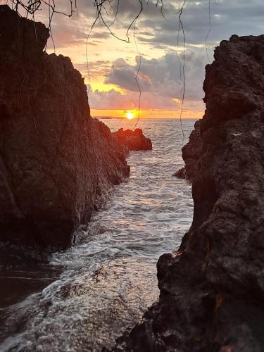 a sunset over the ocean near a rocky coast at Vista Alta Ecolodge Bahia Drake in Drake