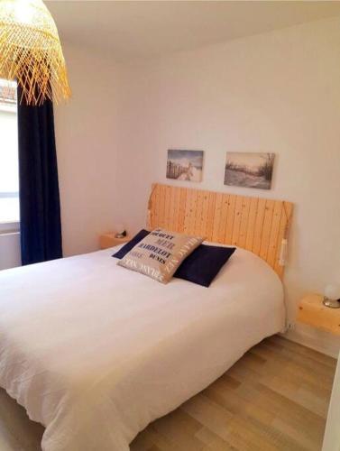 une chambre avec un lit blanc avec un oreiller dessus dans l'établissement L'appartement LA PLAGE, à Le Portel