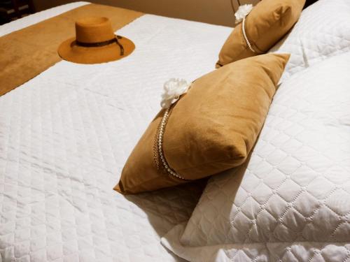 ペルイベにあるCasa com piscina á cinco minutos da praia com vaga para 3 carrosのベッド(枕2つ、帽子付)