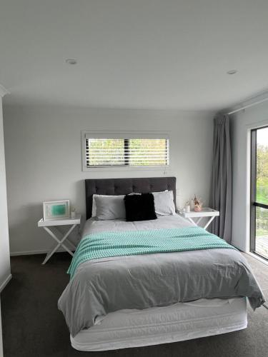 een witte slaapkamer met een groot bed en een raam bij Hobbiton Countryside Sanctuary in Matamata
