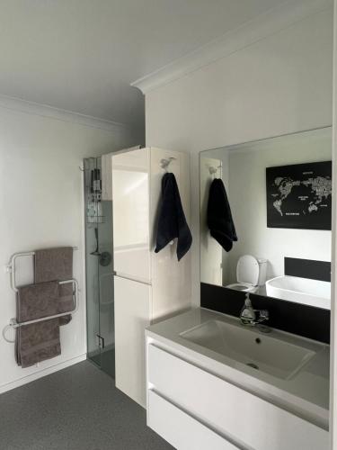 a white bathroom with a sink and a mirror at Hobbiton Countryside Sanctuary in Matamata