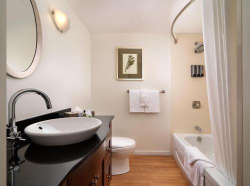 a bathroom with a sink and a toilet and a tub at Huntingdon Hotel and Suites in Victoria