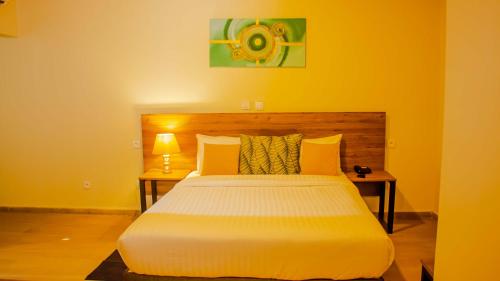 a bedroom with a large white bed with yellow walls at BLUEBAY HOTEL ABIDJAN in Abidjan