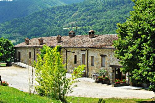 una antigua casa de piedra con montañas en el fondo en Agriturismo Popolano Di Sotto, en Marradi