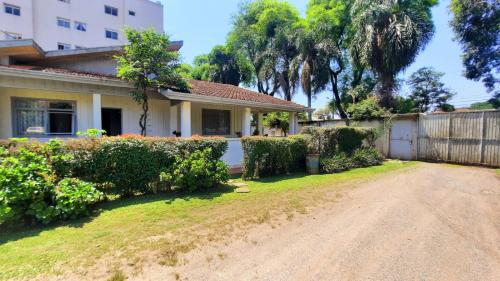 a house with a fence and a dirt road at Quartos em Casa próximo ao Parque Bacacheri in Curitiba