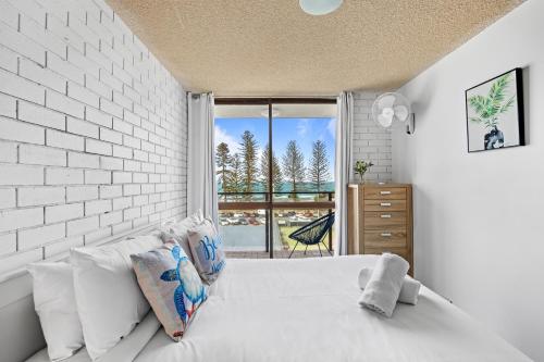 a white bedroom with a white brick wall at Avalon on Alex Beach 2 Bedroom Apartment in Alexandra Headland