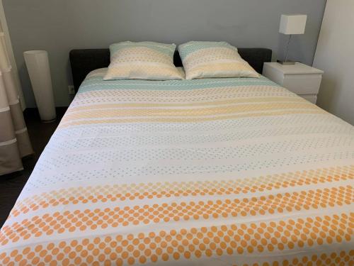 1 cama con edredón y almohadas de color naranja y blanco en Thao, en Serris
