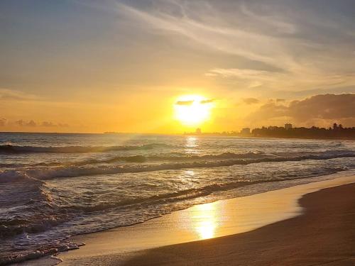 a sunset on a beach with the ocean at Gorgeous 1-Bedroom Beachside Suite in San Juan