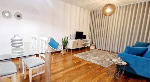 uma sala de estar com cadeiras azuis e uma mesa de vidro em Ocean Pearl Apartment K no Funchal