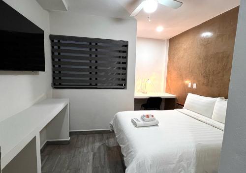 1 dormitorio con 1 cama blanca y TV en LONGVIEW HOME-STUDIOS, en Tepic