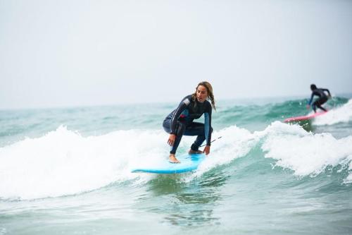 a woman riding a wave on a surfboard in the ocean at Surf Lessons Experience with Hassi in Agadir