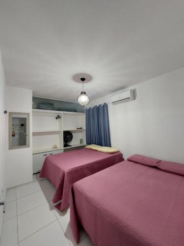 two beds in a bedroom with pink sheets at Zapipou - Apartamento aconchegante para você aproveitar o melhor de Pipa in Pipa