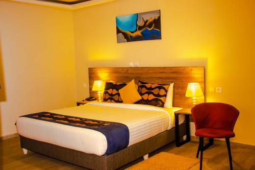 a bedroom with a bed and a red chair at BLUEBAY HOTEL ABIDJAN in Abidjan
