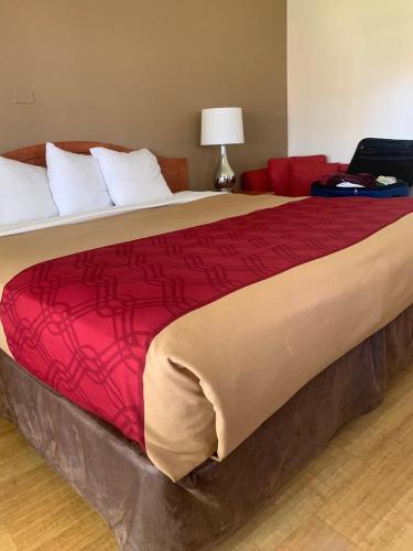 オークランドにあるGarden Inn & Suites Oakland Airportのベッドルーム1室(赤毛布付きの大型ベッド1台付)