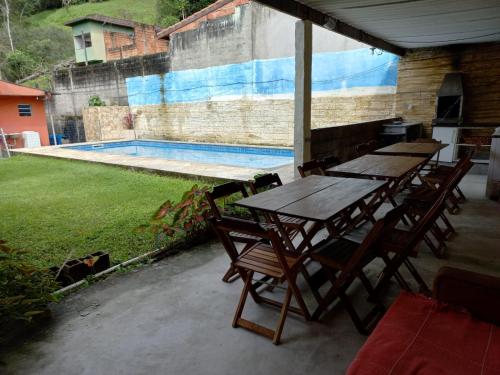 a group of tables and chairs next to a swimming pool at Residência in Caraguatatuba