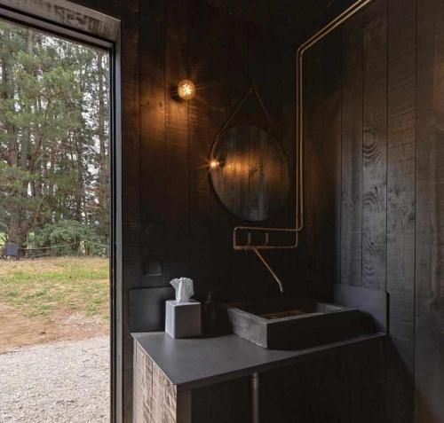 a black bathroom with a sink and a mirror at A Leira 116 Cabañas de diseño in Sarria