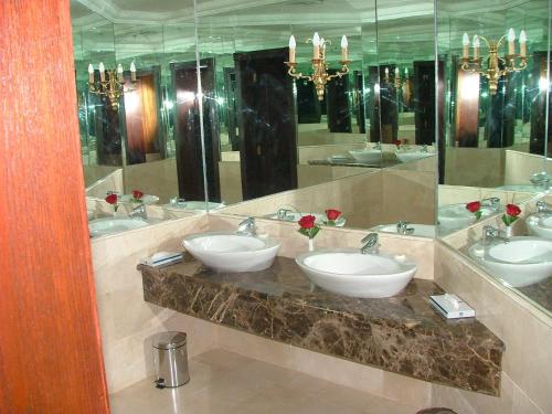 a bathroom with three sinks and a large mirror at Le Royal Express Salmiya in Kuwait