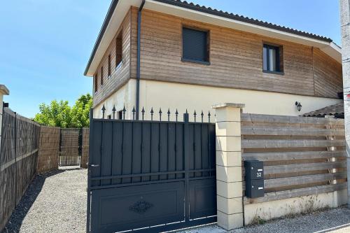 una casa con una puerta negra y una valla en Cosy town house in Bordeaux stone en Villenave-dʼOrnon
