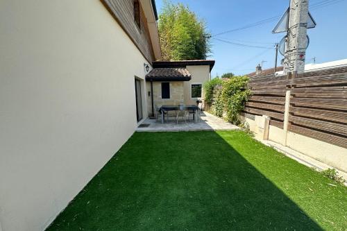 a backyard with a green lawn next to a building at Cosy town house in Bordeaux stone in Villenave-dʼOrnon
