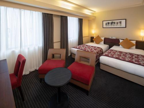 Cette chambre d'hôtel comprend deux lits, une table et des chaises. dans l'établissement Art Hotel Joetsu, à Joetsu