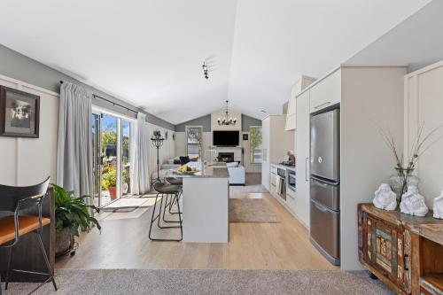 an open kitchen and living room with white appliances at Hunter Lodge - Papamoa Beach Holiday Home in Papamoa