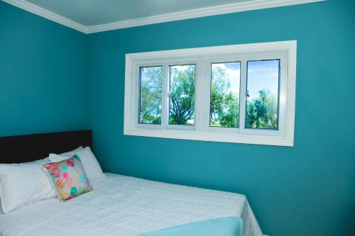 a blue bedroom with a bed and two windows at Sheer Bliss BeachView Apt #1 in Georgetown