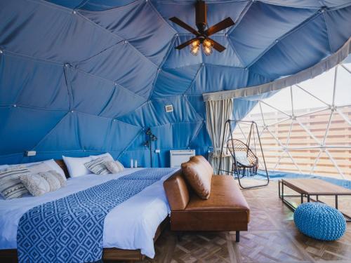 a bedroom with a blue tent with a bed and a ceiling at Seage Torami Coastside in Ichinomiya