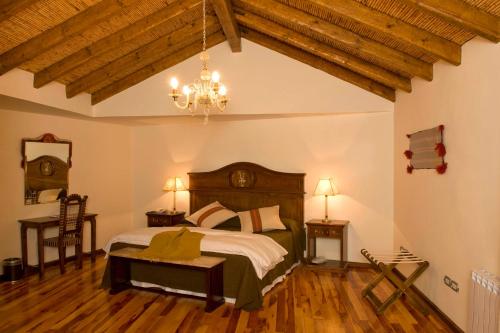 Un dormitorio con una cama grande y una lámpara de araña. en Hotel Marqués De Tojo en Purmamarca
