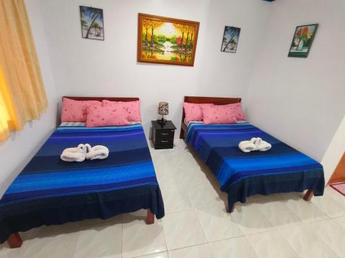 two beds in a room with pink and blue sheets at Hadefe Resort in El Nido