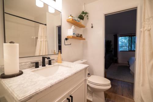 W łazience znajduje się umywalka, toaleta i lustro. w obiekcie Beach Shack w mieście Huntington Beach