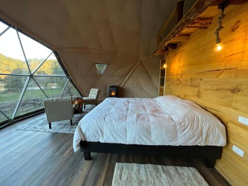 ein Schlafzimmer in einem Zelt mit einem Bett und einem Stuhl in der Unterkunft Alma Andina in Puelo