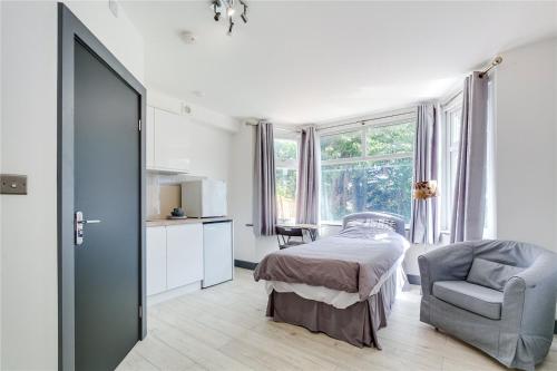 1 dormitorio con 1 cama, 1 silla y 1 ventana en Modern Designer Studio Flat London, en Londres