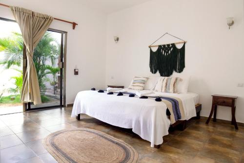 a white bedroom with a bed and a large window at hotel stella maris tulum in Tulum