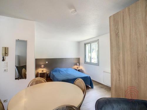 une chambre avec un lit, une table et des chaises dans l'établissement Studio cosy à 50m des Thermes de Lamalou-les-Bains avec terrasse, wifi et animaux acceptés - FR-1-451-46, à Lamalou-les-Bains