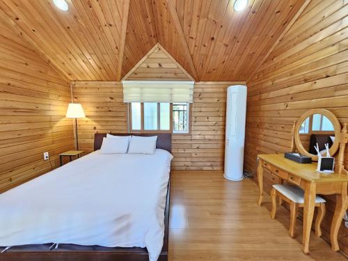 a bedroom in a wooden cabin with a bed and a desk at Old Man And Sea in Seogwipo