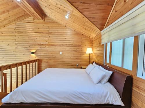 a bedroom with a bed in a wooden room at Old Man And Sea in Seogwipo