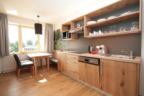 a kitchen with wooden cabinets and a sink and a table at Aktiv & Sport Apartments Oberjörg in Rattendorf
