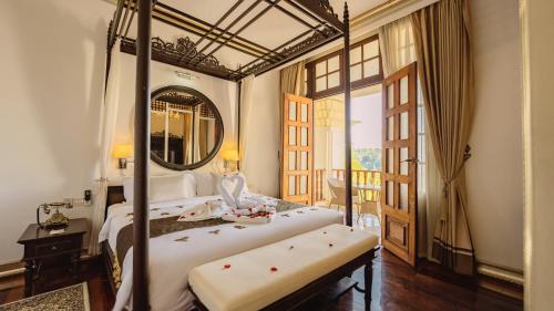 a bedroom with a large bed and a mirror at JingLand Hotel Luangprabang in Luang Prabang