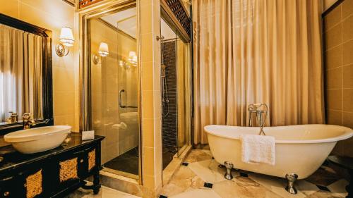 a bathroom with a tub and a sink and a mirror at JingLand Hotel Luangprabang in Luang Prabang