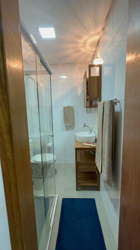 a bathroom with a glass shower and a sink at Biquinha - Praça 22 de Janeiro in São Vicente